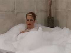 Blondine seift sich in der Badewanne Füße ein